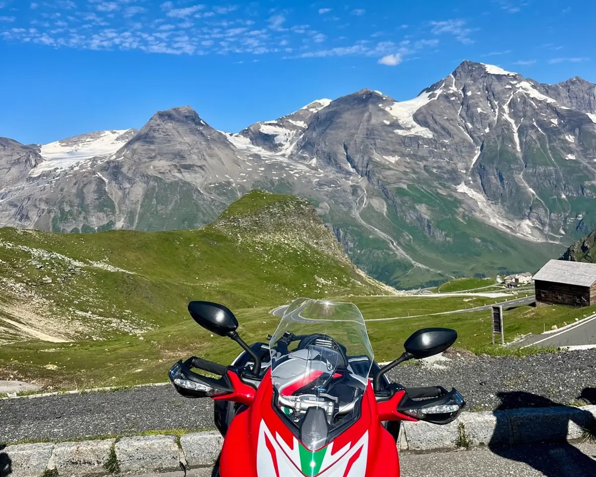 Motorrad vor schneebedeckten Gipfeln an einer Alpenstraße